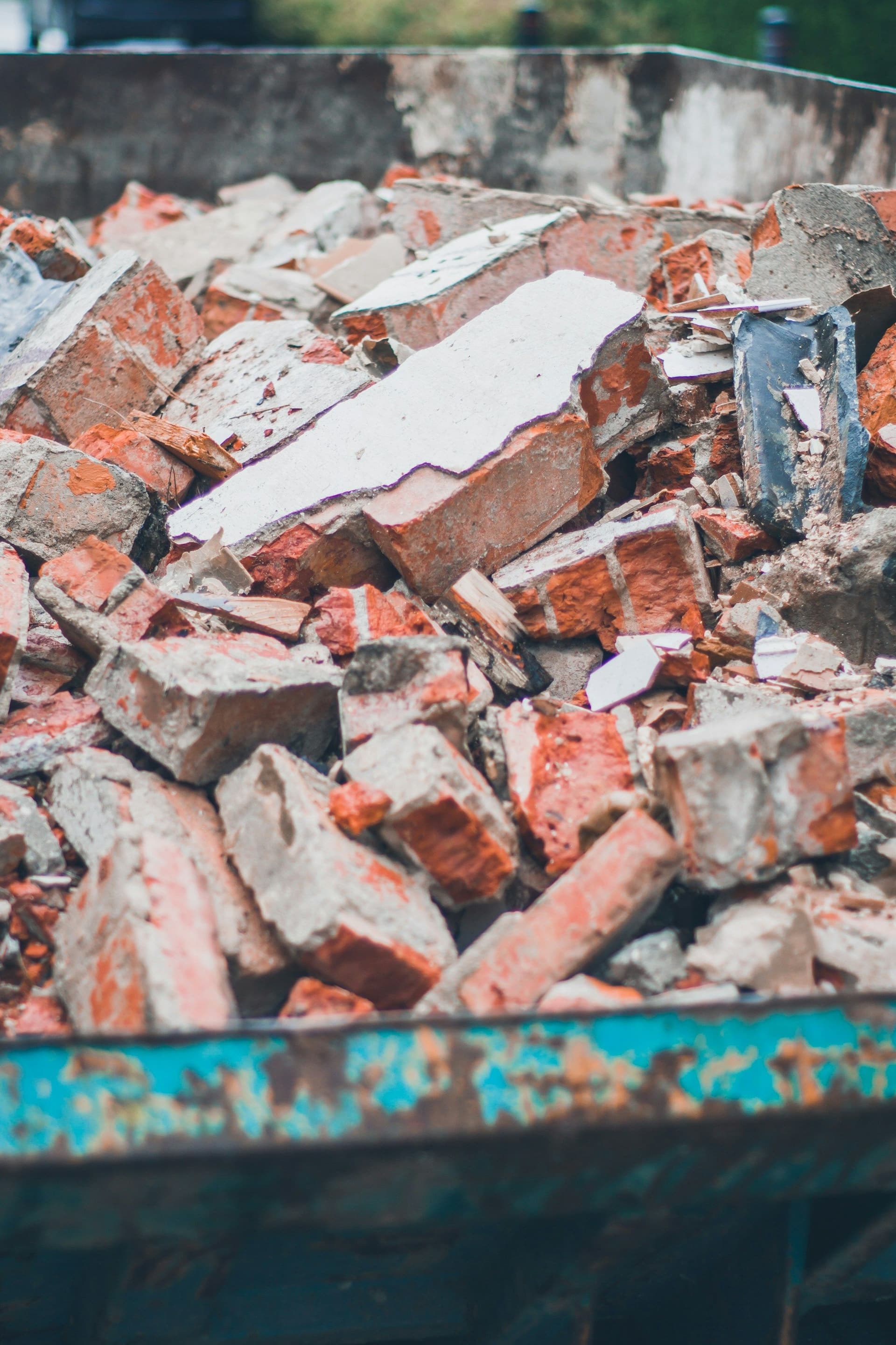 A skip filled with broken red brick and white plaster rubble