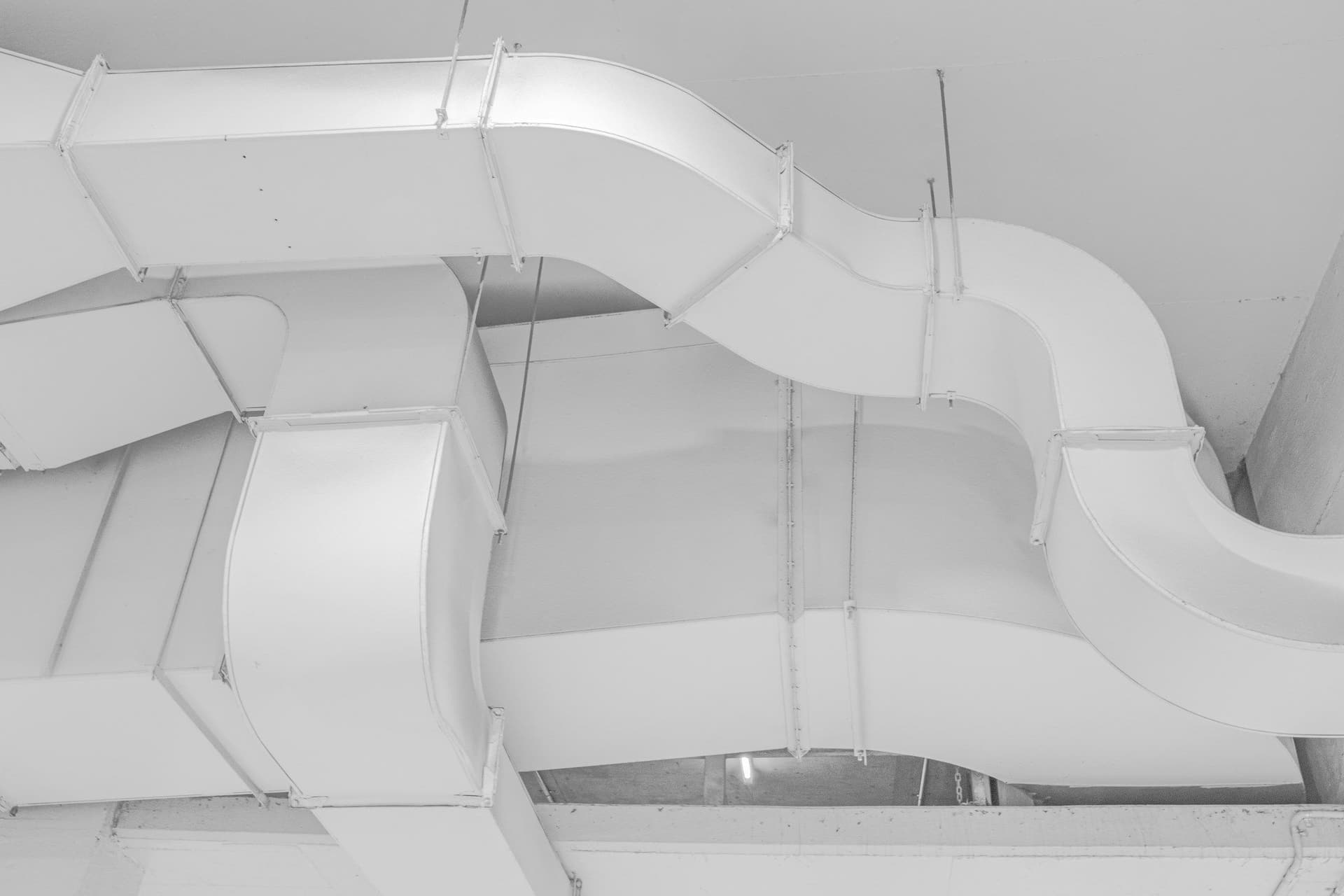 White air ducts bend and branch along a ceiling