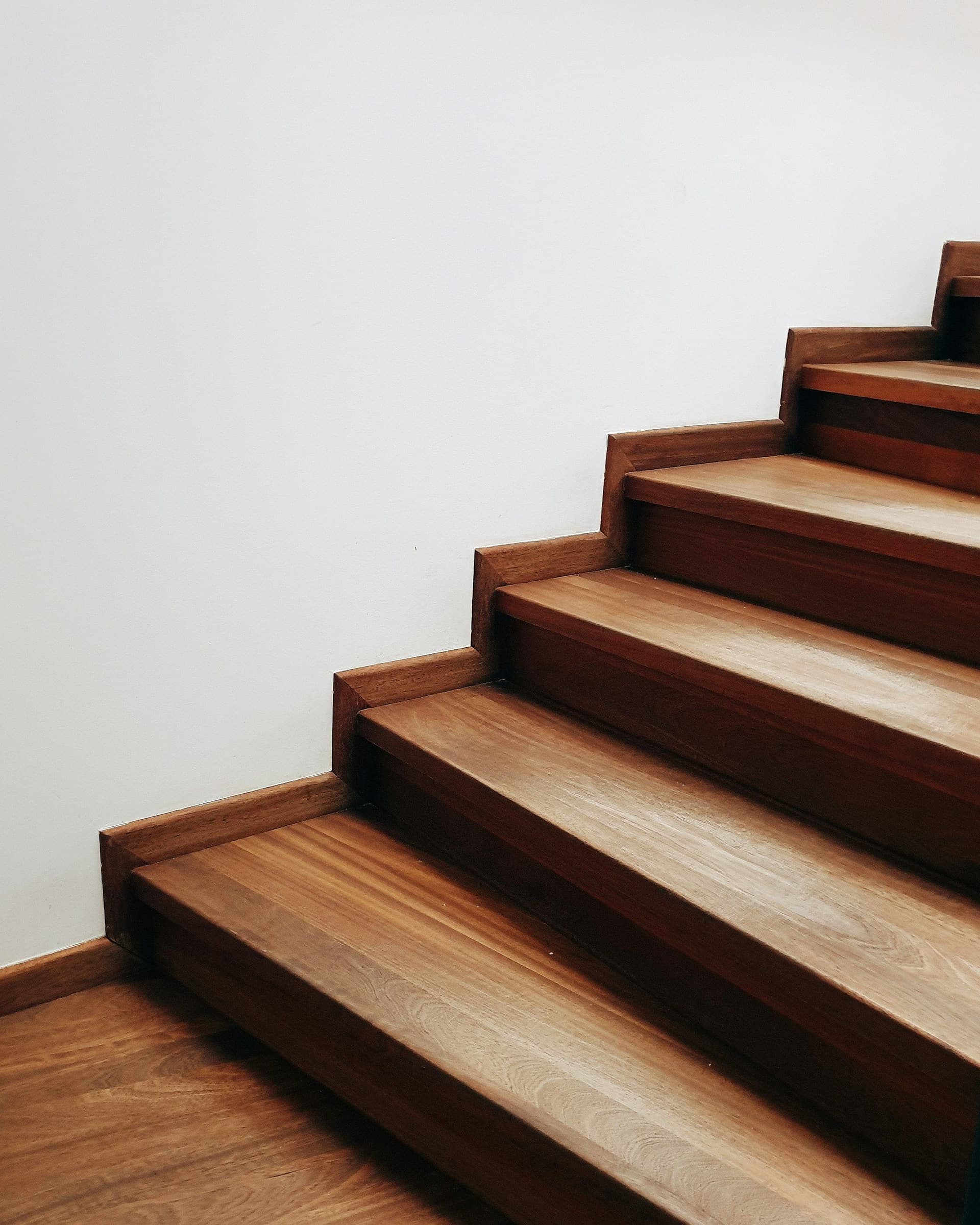 Timber stair treads rising beside a white wall