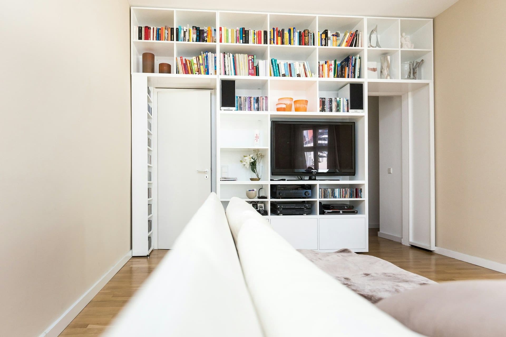 White built-in wall unit with open shelves, a TV recess and a door set into the bookcase