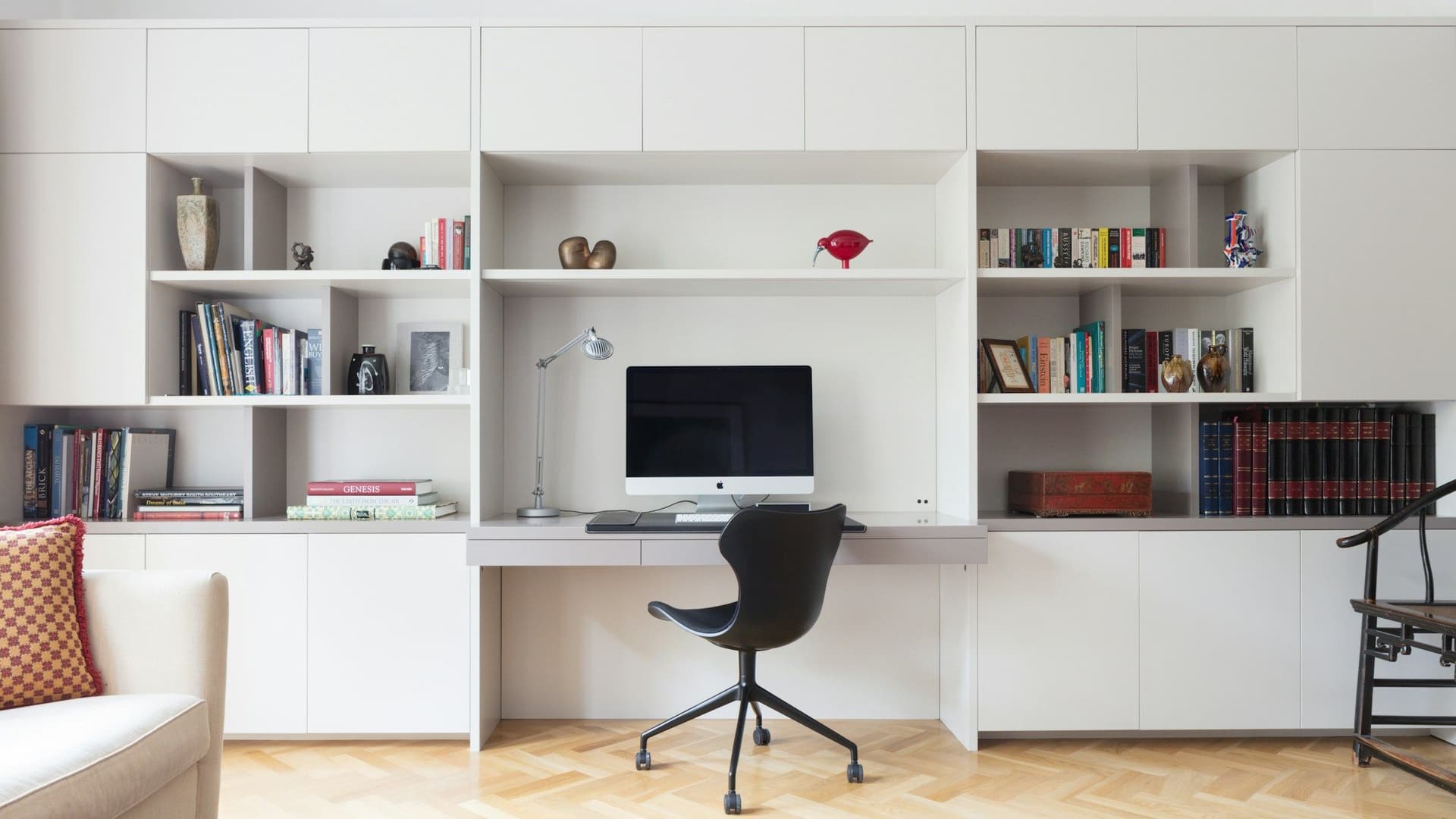 White built-in wall of shelves and cabinets with a desk, a computer and a black chair