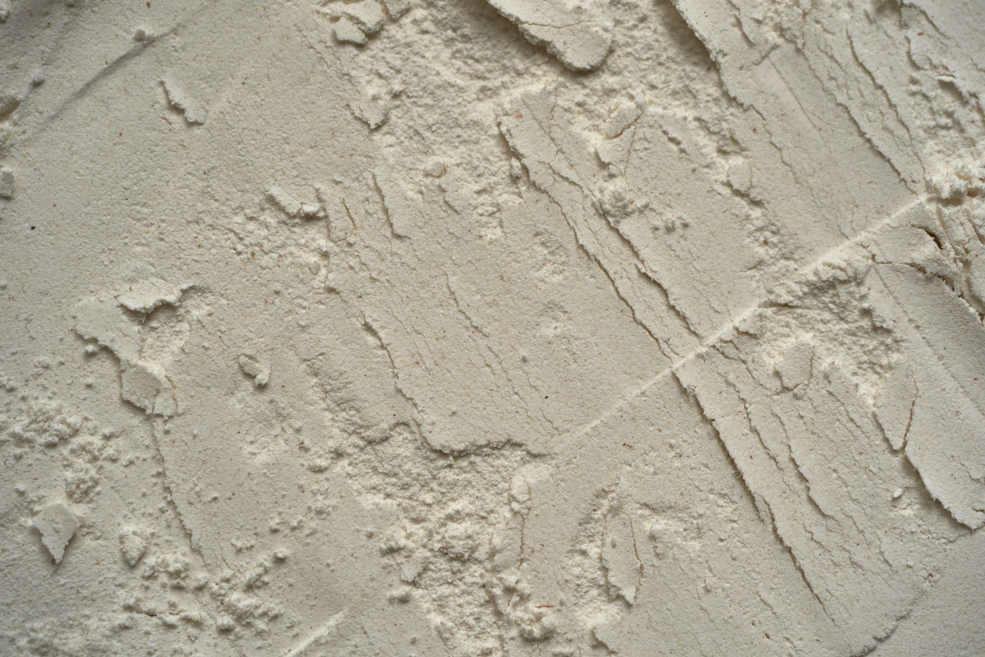 Rough plaster wall surface partly covered in white paint