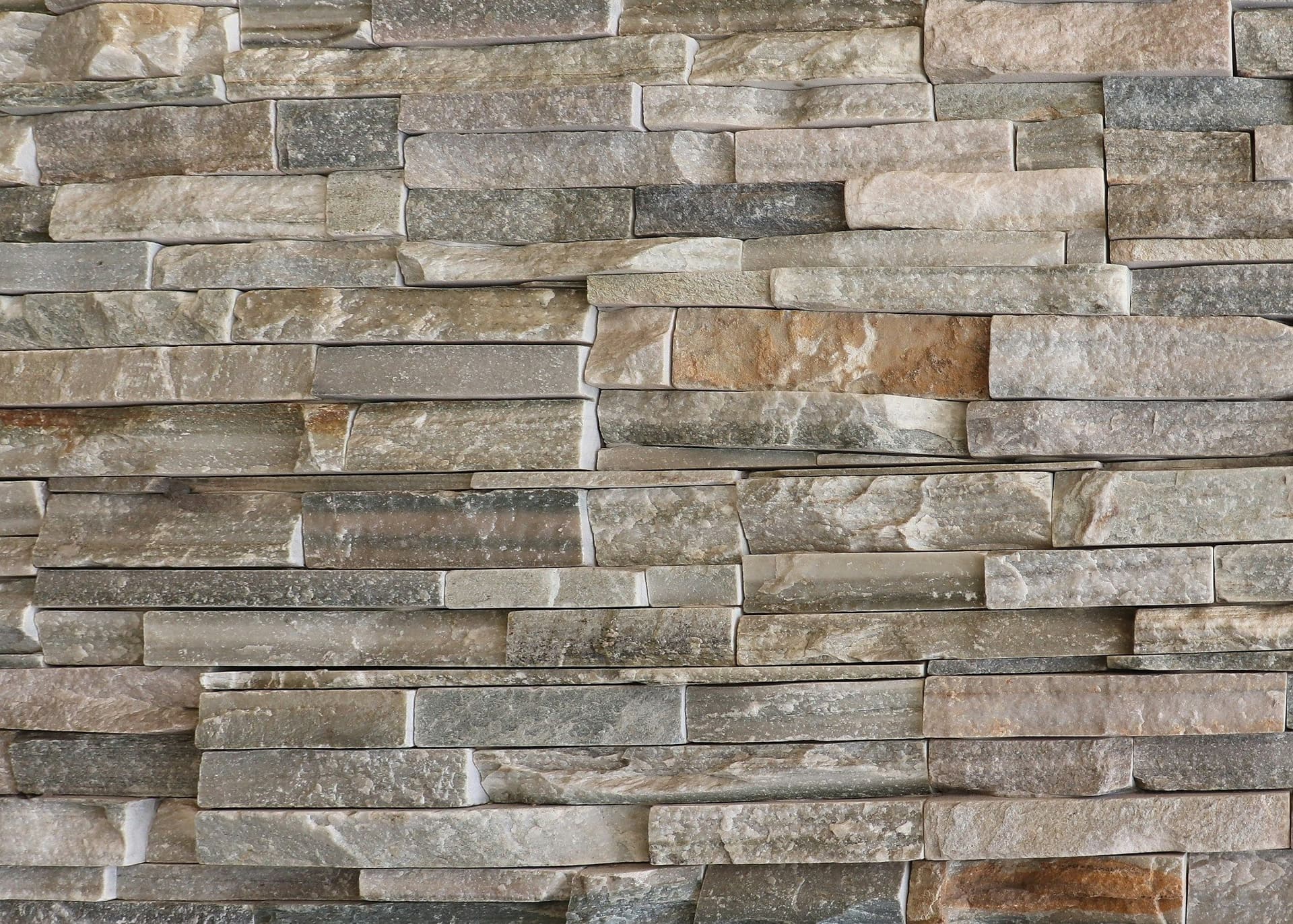 Layered natural stone cladding in beige and gray strips on an exterior wall