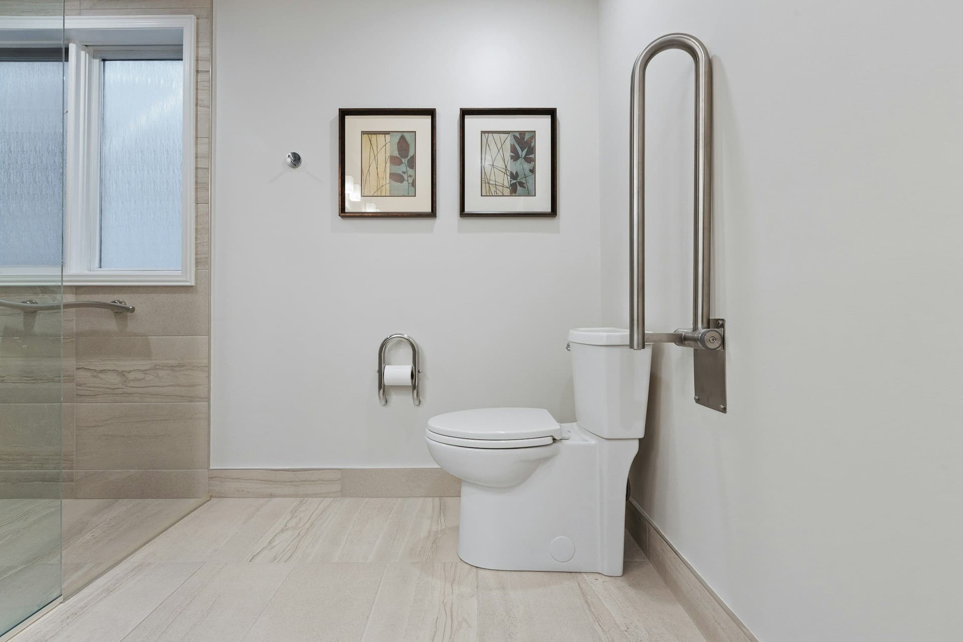 Bathroom with a tall U-shaped grab rail beside the toilet, a window and a glass shower screen