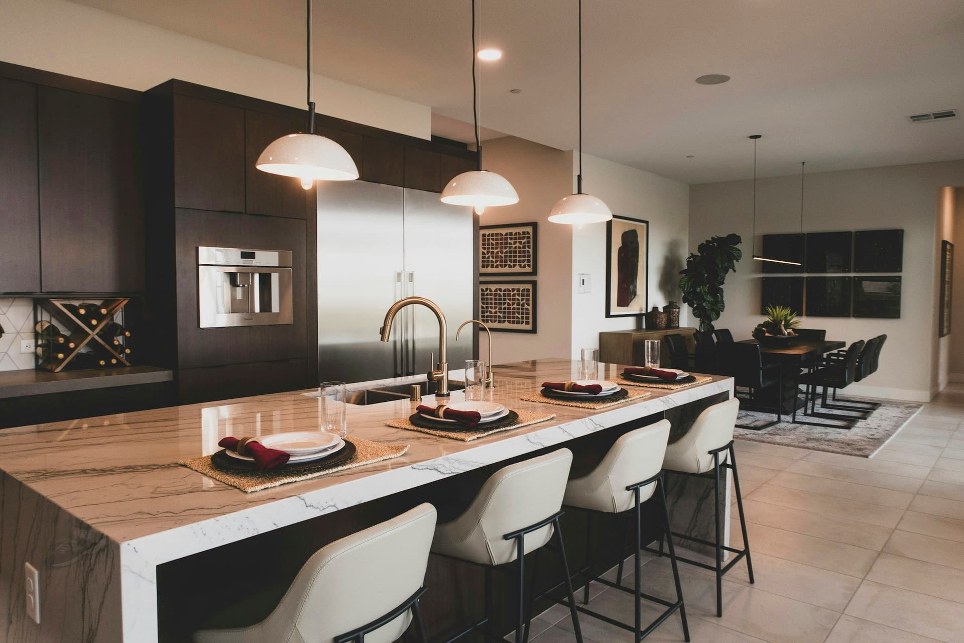 Kitchen with dark cabinets and a marble waterfall island with a wood-toned surface and stools