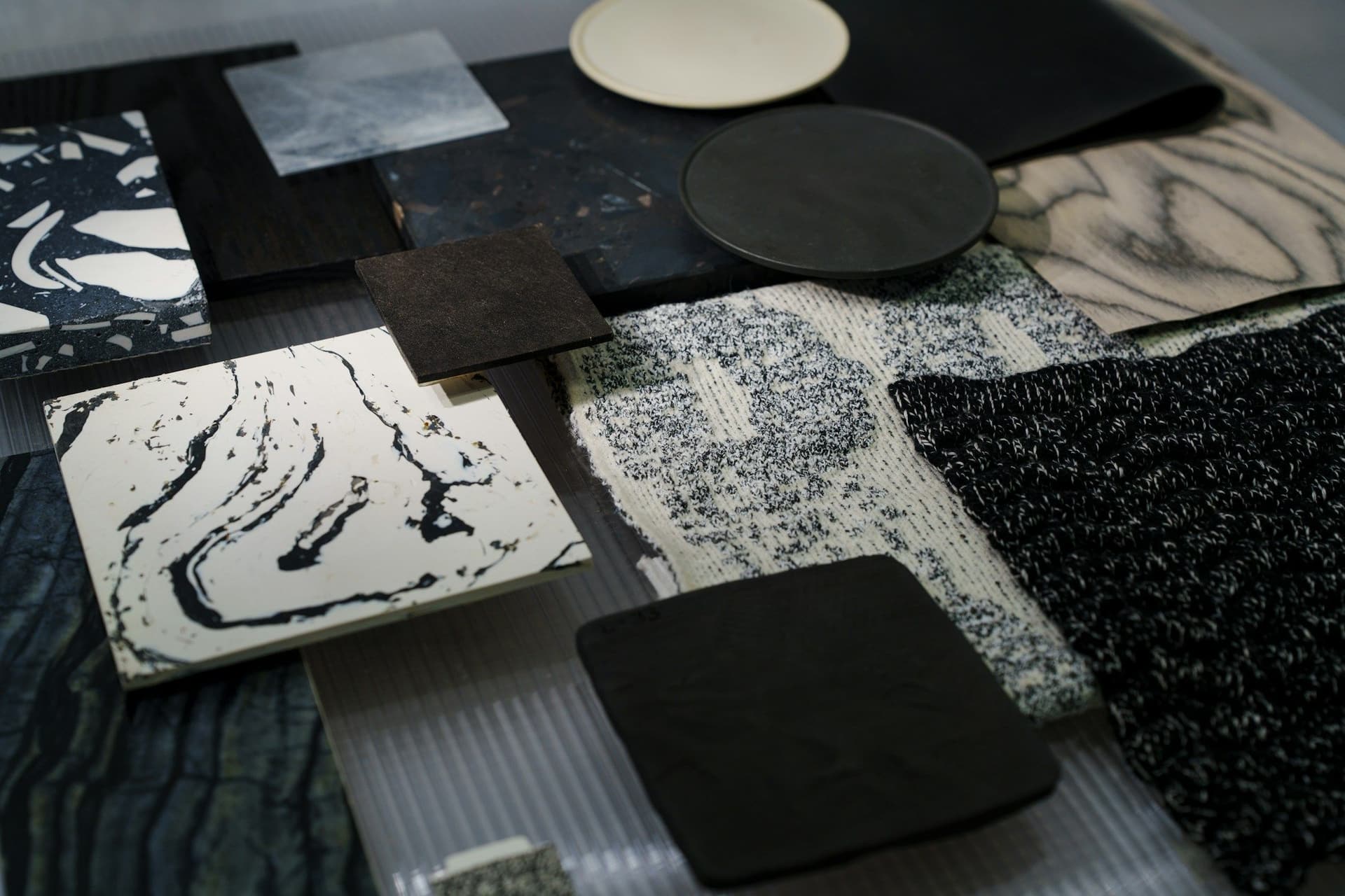 Marble, terrazzo, wood veneer and textured fabric samples laid out together on a dark surface