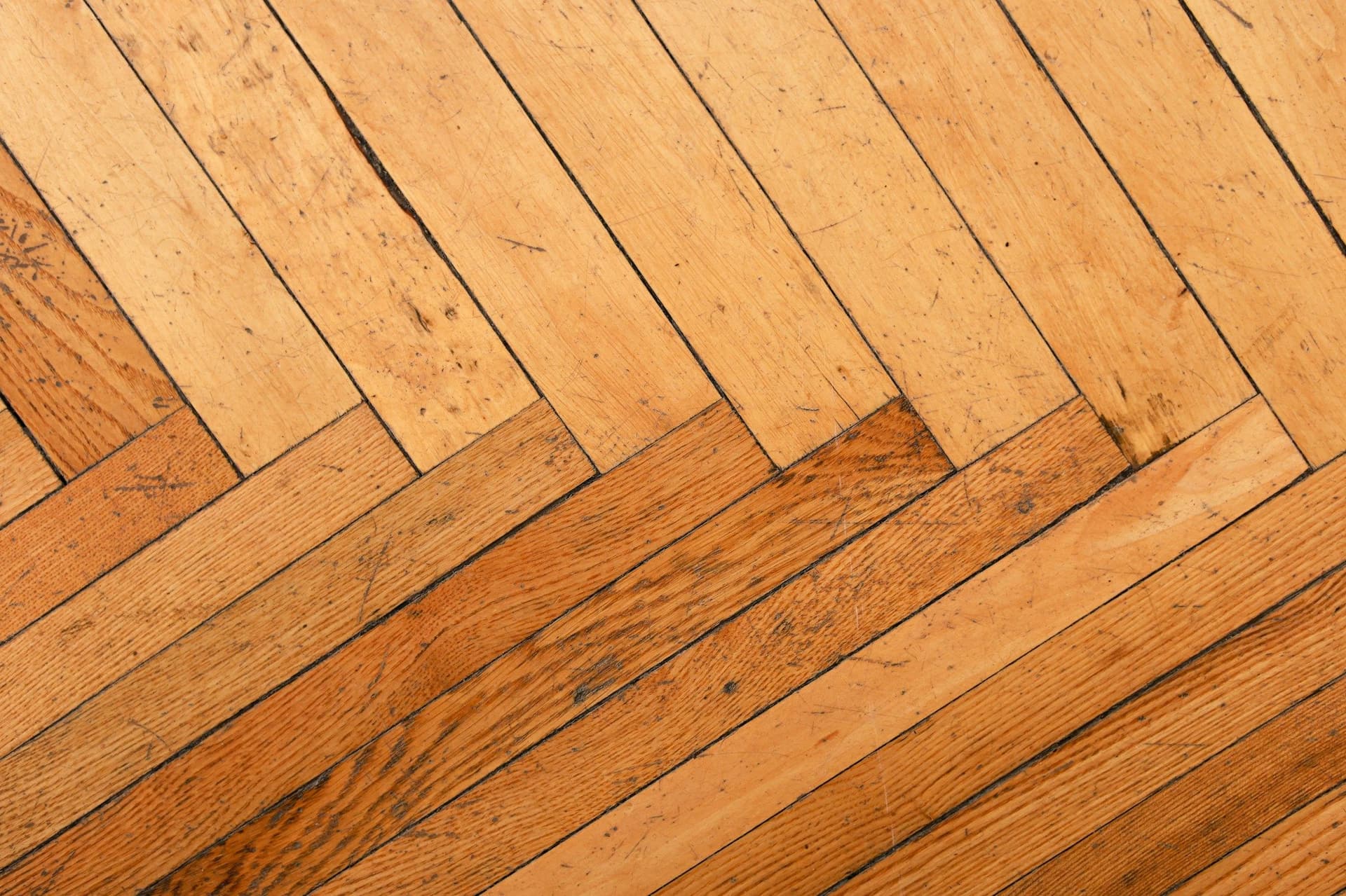 Close-up of a warm honey-toned herringbone wood floor with planks in a zigzag pattern