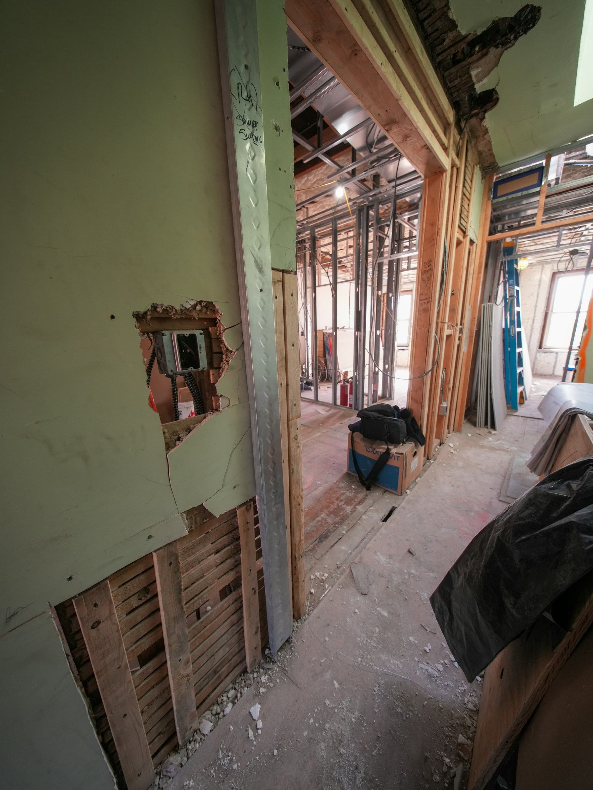 An interior wall opened up to its timber framing during a renovation, with tools on the floor