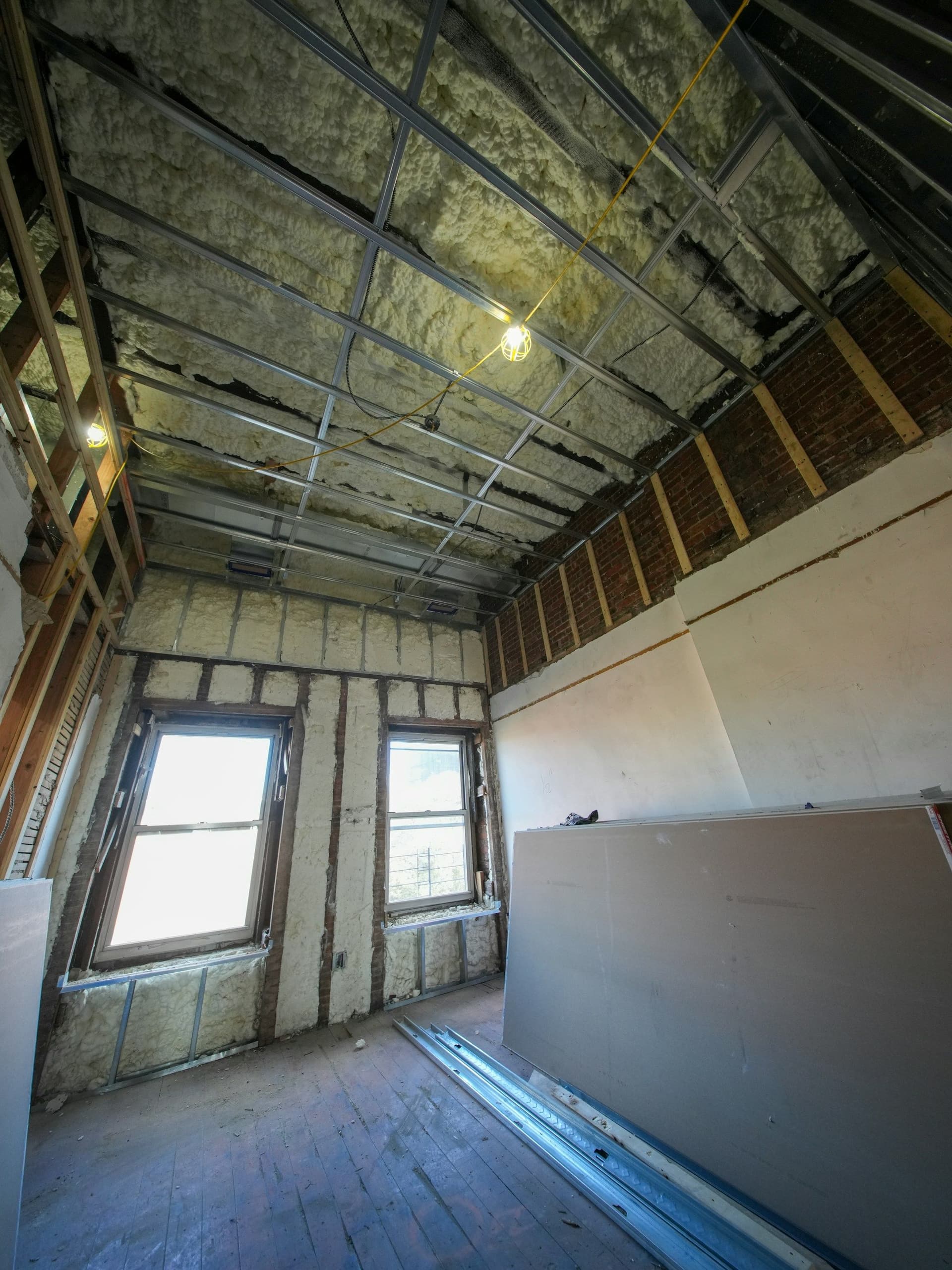 Attic room under renovation with sprayed insulation on the sloped roof and walls, metal framing and drywall sheets