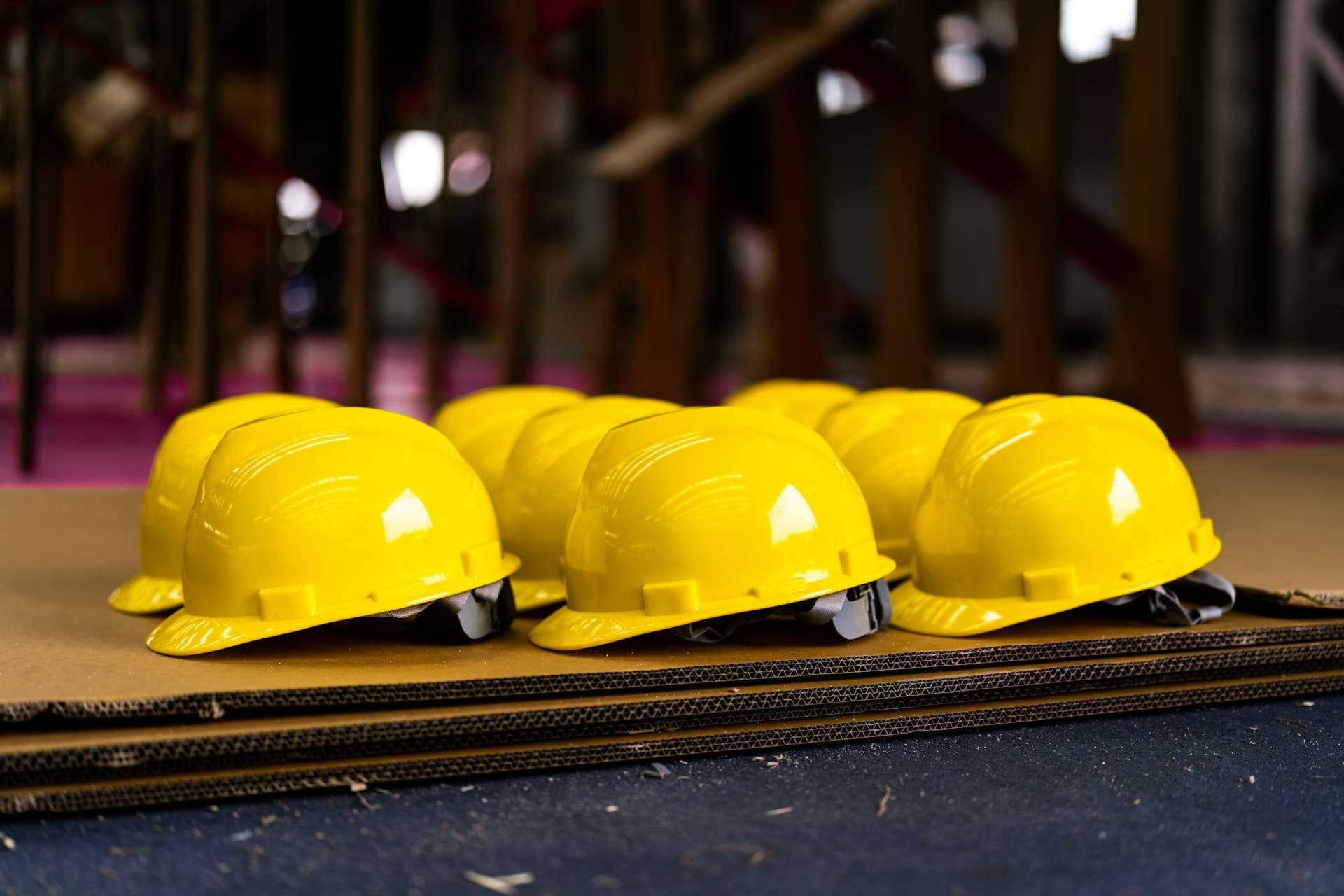 Yellow hard hats lined up on a flat board inside a building under construction