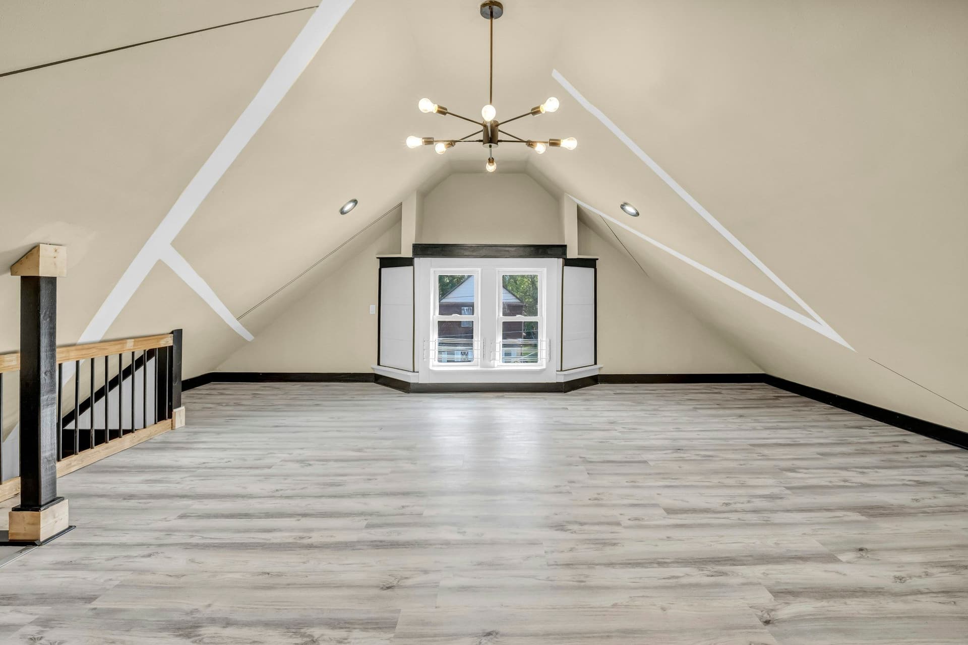 Attic room with a stair opening and railing, sloped ceilings, a window and a wood-look floor